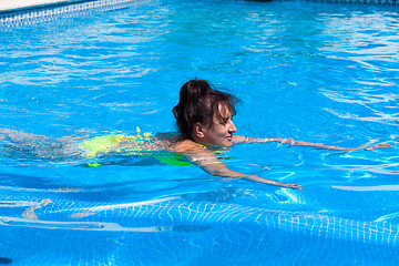 Image showing Middle-aged woman swims in the swimming pool