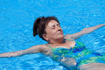 Image showing Middle-aged woman swims in the swimming pool