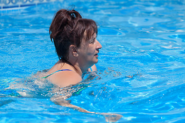 Image showing Middle-aged woman swims in the swimming pool