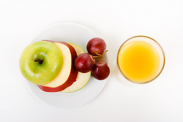 Image showing Apple, grapes on a plate and a glass of orange juice