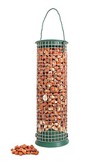 Image showing Bird feeder filled with peanuts and some nuts lying loose