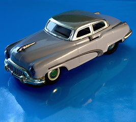 Image showing old gray toy car against a blue reflective background