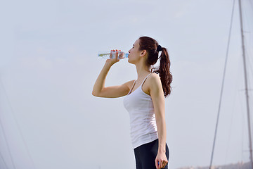 Image showing Young beautiful woman drinking water after fitness exercise