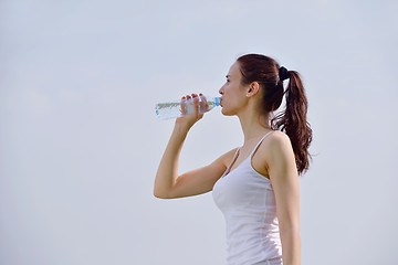 Image showing Young beautiful woman drinking water after fitness exercise