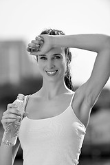 Image showing Young beautiful woman drinking water after fitness exercise