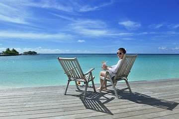 Image showing Beautiful young woman with a drink by the sea