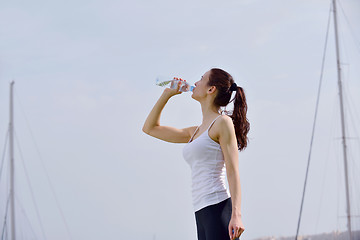 Image showing Young beautiful woman drinking water after fitness exercise