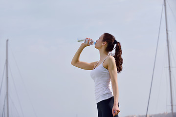 Image showing Young beautiful woman drinking water after fitness exercise