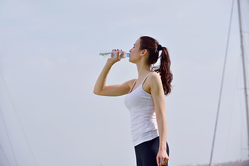 Image showing Young beautiful woman drinking water after fitness exercise