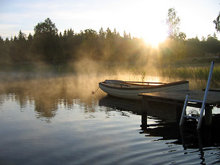 Image showing Small boat in a misty lake at sunrise.