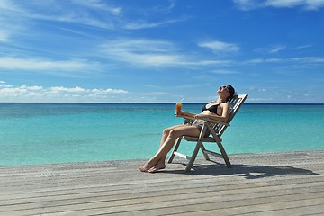 Image showing Beautiful young woman with a drink by the sea