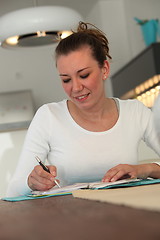 Image showing Young woman working at home at a table