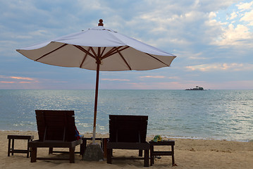 Image showing Two beds and an umbrella on the beach at sunset