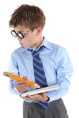 Image showing Schoolboy wearing glasses holding book and pencil and looking si