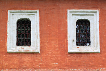 Image showing Two windows with bars on the red wall