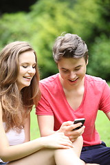 Image showing Young teenage couple laughing at an sms