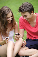 Image showing Couple of teenagers looking at their mobile phones