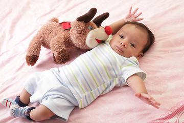 Image showing hispanic baby with teddy bear laying on bed