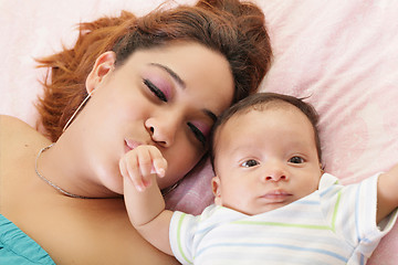Image showing Hispanic mother kissing her baby hand.  Focus on the mother.