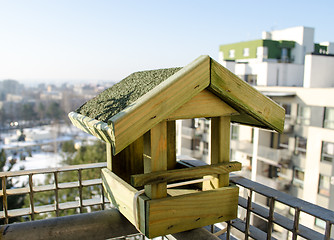 Image showing wooden small bird feeder on the balcony edge  