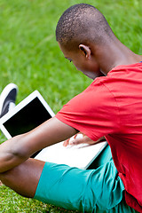 Image showing young smiling african student sitting in grass with notebook