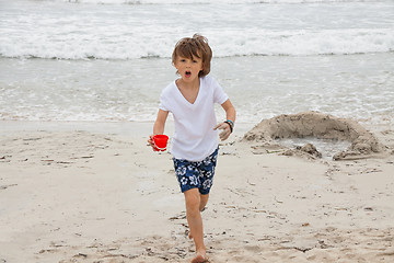 Image showing cute little boy playing in sand on beach in summer
