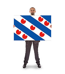 Image showing Smiling businessman holding a big card, flag of the dutch provin