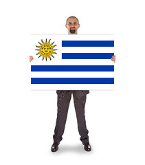 Image showing Smiling businessman holding a big card, flag of Uruguay