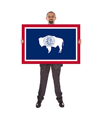 Image showing Smiling businessman holding a big card, flag of Wyoming