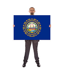 Image showing Smiling businessman holding a big card, flag of New Hampshire