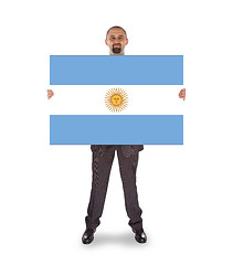 Image showing Smiling businessman holding a big card, flag of Argentine