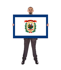 Image showing Smiling businessman holding a big card, flag of West Virginia