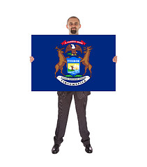 Image showing Smiling businessman holding a big card, flag of Michigan