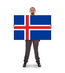 Image showing Smiling businessman holding a big card, flag of Iceland