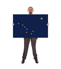 Image showing Smiling businessman holding a big card, flag of Alaska