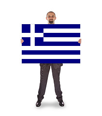Image showing Smiling businessman holding a big card, flag of Greece