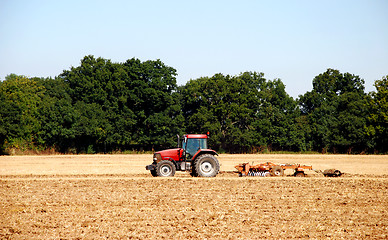 Image showing Tractor and harrow cultivating the soil