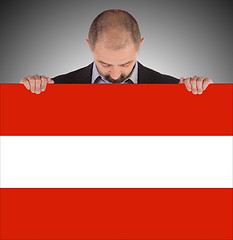 Image showing Smiling businessman holding a big card, flag of Austria