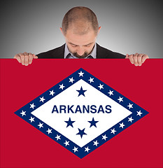 Image showing Smiling businessman holding a big card, flag of Arkansas