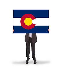 Image showing Smiling businessman holding a big card, flag of Colorado