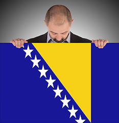 Image showing Smiling businessman holding a big card, flag of Bosnia and Herze