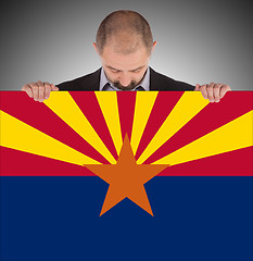 Image showing Smiling businessman holding a big card, flag of Arizona