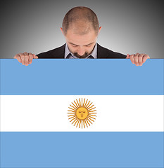 Image showing Smiling businessman holding a big card, flag of Argentine