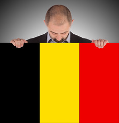 Image showing Smiling businessman holding a big card, flag of Belgium