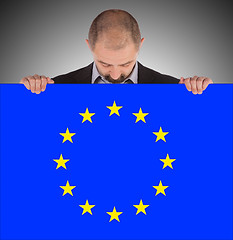 Image showing Smiling businessman holding a big card, flag of the European Uni