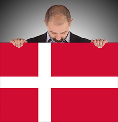 Image showing Smiling businessman holding a big card, flag of Denmark