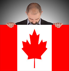 Image showing Smiling businessman holding a big card, flag of Canada