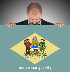 Image showing Smiling businessman holding a big card, flag of Delaware