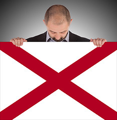 Image showing Smiling businessman holding a big card, flag of Alabama