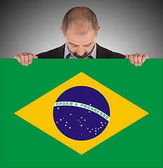 Image showing Smiling businessman holding a big card, flag of Brazil